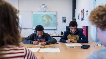 Two smiling students sit at a table and work on Van Gogh-related projects